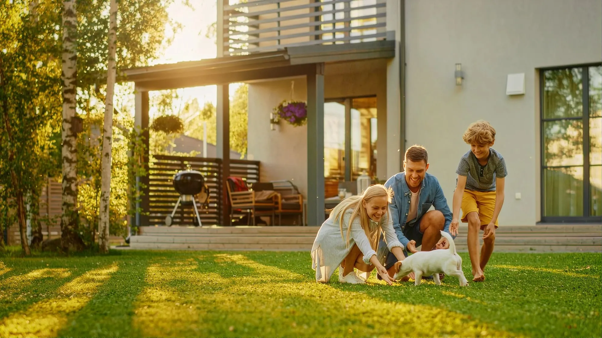 A family playing with their puppy on the lawn behind their house